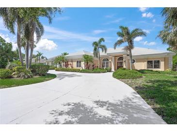 Sprawling ranch-style home with a circular driveway and lush tropical landscaping at 8 Dominica Dr, Englewood, FL 34223