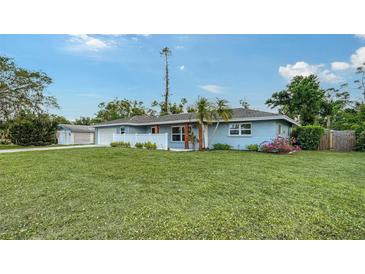 Charming single-story blue home with a white fence, lush green lawn, and welcoming curb appeal at 2825 Pinecrest St, Sarasota, FL 34239