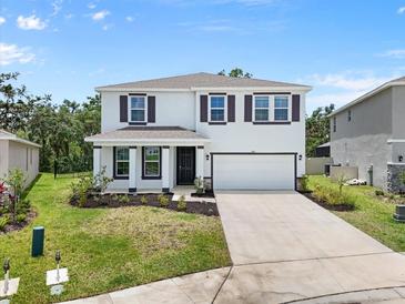 Attractive two-story home featuring a manicured lawn, front porch, two-car garage, and complementary dark shutters at 4015 Quiet Rain Ct, Palmetto, FL 34221
