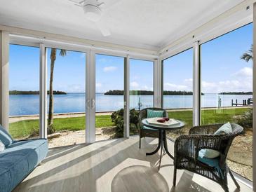 Bright sunroom with panoramic water views, wicker furniture, and a ceiling fan for optimal comfort at 4310 Falmouth Dr # 105, Longboat Key, FL 34228