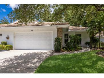 Charming home featuring a two-car garage, red tile roof, and well-manicured landscaping at 5712 Garden Lakes Dr, Bradenton, FL 34203