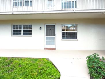 The front of this property features a front door and white walls with lush landscaping at 970 Virginia St # 109, Dunedin, FL 34698