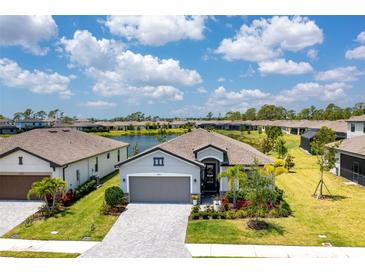 Inviting single-Gathering home featuring manicured lawn, mature landscaping and paver driveway with a water view in the background at 19801 Fishhawk Trl, Venice, FL 34293