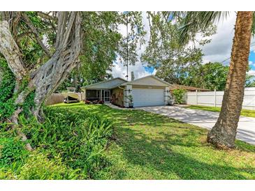 Charming single-story home with a well-manicured lawn, mature trees, and a two-car garage on a sunny day at 4115 2Nd Nw Ave, Bradenton, FL 34209