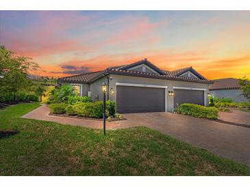 Charming villa exterior with a tile roof, brick driveway, landscaping, and a colorful sunset sky at 6250 Grandview Hill Ct, Bradenton, FL 34203