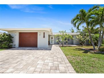 Charming single-story home featuring a well-manicured lawn, and paver driveway leading to the attached garage at 6841 Roxbury Dr, Sarasota, FL 34231