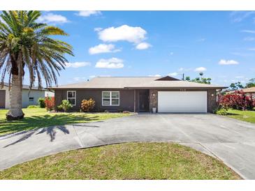 Charming single-story home featuring an attached two-car garage, palm tree, and well-maintained landscaping at 710 Beverly Rd, Venice, FL 34293