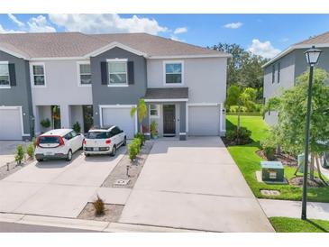 Two-story townhome features a gray facade, manicured lawn and driveway for two cars at 8628 Milestone Dr, Sarasota, FL 34238