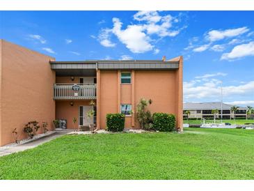 Two-story condo featuring a well-maintained lawn, vibrant landscaping and a balcony overlooking the grounds at 1355 Rock Dove Ct # 1-2, Punta Gorda, FL 33950