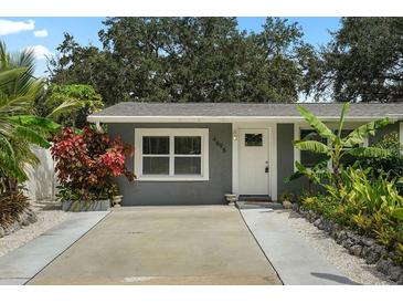 Inviting front exterior showcasing lush tropical landscaping, enhanced by a well-maintained lawn and concrete driveway at 4695 86Th N Ave, Pinellas Park, FL 33782
