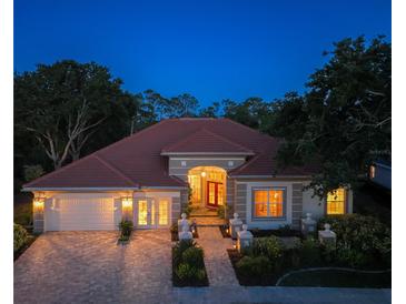 Stunning exterior view of home with landscaped front yard, brick driveway, and beautiful roofline at twilight at 766 Shadow Bay Way, Osprey, FL 34229