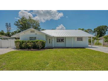 Charming single-story home featuring a well-manicured lawn, fresh landscaping, and a durable silver metal roof at 1461 Porpoise Rd, Venice, FL 34293