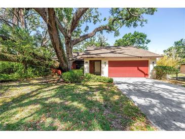 Charming single-story home with a red garage door, mature trees, and a spacious driveway at 3934 Brookside Dr, Sarasota, FL 34231