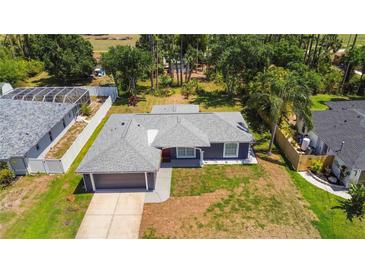 Aerial view of a well-maintained home with a gray roof, green lawn, and mature trees in a desirable neighborhood at 4664 Hegira St, North Port, FL 34286