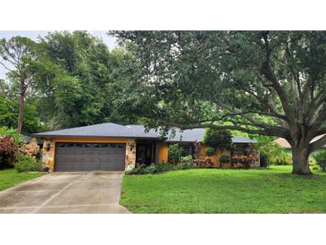 Charming home featuring a stone facade, two-car garage, and inviting curb appeal with mature landscaping at 4873 Huntleigh Dr, Sarasota, FL 34233