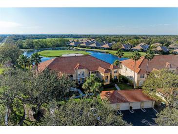 Elegant condo building featuring a terracotta roof with scenic views overlooking a lush golf course and serene lake at 8422 Wethersfield Run # 103, Lakewood Ranch, FL 34202