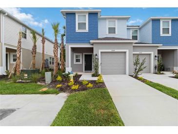 Charming two-story home with a well-manicured lawn and inviting front entrance with a gray garage door at 9064 Driven Snow St, Sarasota, FL 34241