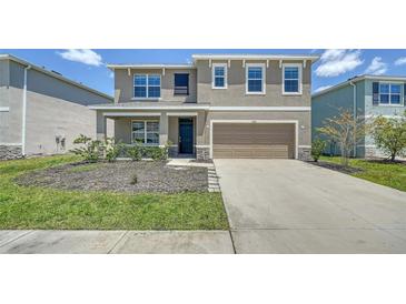 Inviting two-story home featuring a two-car garage, well-manicured lawn and a welcoming front porch at 12732 Lateral Root Dr, Sarasota, FL 34238