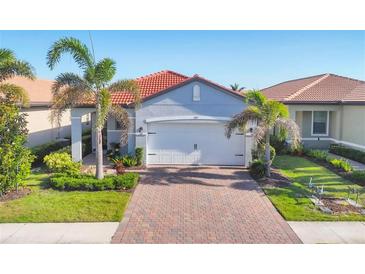 Charming single-story home with a red tile roof, lush landscaping, and a brick driveway at 197 Villoresi Blvd, Nokomis, FL 34275
