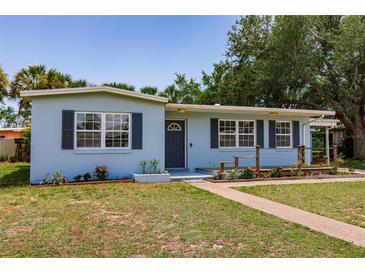 Charming light blue single-story home featuring mature landscaping and a walkway to the front door at 22275 Belinda Ave, Port Charlotte, FL 33952