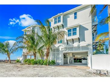 Three-story beach house featuring white exterior, palm trees, an open garage, and a private entrance at 2500 Gulf N Dr, Bradenton Beach, FL 34217