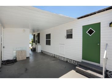 Covered carport and entrance with green door and white vinyl siding, offering protection from the elements at 307 White Oak Way, Sarasota, FL 34237