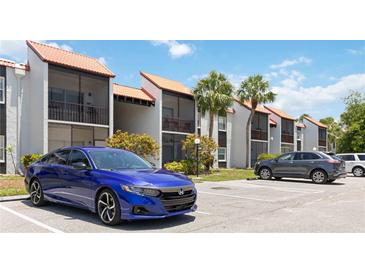 A condo building featuring a terracotta roof and balconies, complemented by tropical landscaping and a convenient parking area at 3269 Beneva Rd # 103, Sarasota, FL 34232