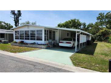 Charming manufactured home featuring a carport and a cozy sunroom enclosed with large awning style windows at 3308 Oakwood S Blvd, Sarasota, FL 34237