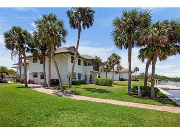 Beautiful two-story home with a lush green lawn and mature palm trees at 4234 Gulf Of Mexico Dr # G2, Longboat Key, FL 34228