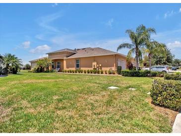 Tan home featuring a well manicured lawn, trimmed hedges, and a neatly kept garden at 635 Chipper Dr, Sun City Center, FL 33573