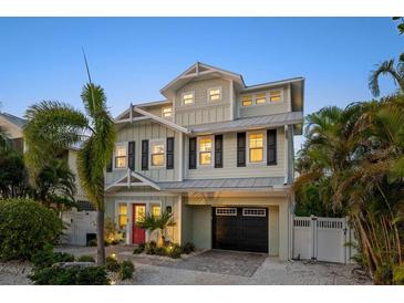 Charming two-story home with a black garage door and a landscaped yard, creating an inviting curb appeal at 704 Gladiolus St, Anna Maria, FL 34216