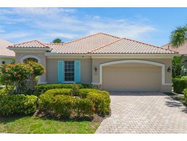 Charming home featuring a tile roof, two-car garage, manicured landscaping, and a brick-paved driveway at 7164 Rue De Palisades # 5, Sarasota, FL 34238