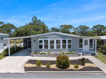 Charming single-story home with a light-blue exterior, landscaped flower beds, and a spacious carport at 842 Jolanda Cir, Venice, FL 34285