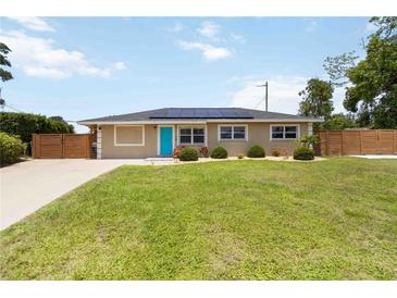 Charming single-story home with a well-manicured lawn, blue front door, solar panels, and a wooden fence at 1212 Princeton Ave, Bradenton, FL 34207