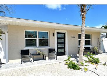 Charming home featuring a modern front door, neutral paint, well manicured landscaping and seating at 2908 Gulf Dr, Holmes Beach, FL 34217