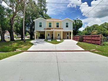 Charming two-story duplex with a large driveway, lawn, and quaint curb appeal on a sunny day at 4209 W Woodlawn Ave, Tampa, FL 33614