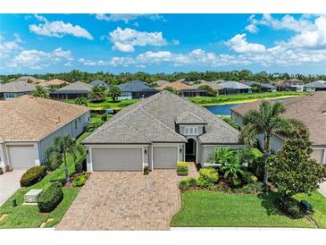 Stunning aerial view of a home featuring a three-car garage, lush landscaping, and a picturesque lake view at 518 Chantilly Trl, Bradenton, FL 34212