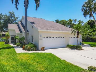 Charming home featuring a three-car garage, well-maintained lawn, and lush tropical landscaping at 6222 Country Club Way, Sarasota, FL 34243