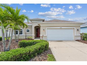 Charming single-story home with a two-car garage, manicured landscaping, and beautiful palm trees at 12642 Cara Cara Loop, Bradenton, FL 34212