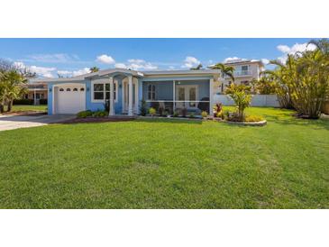 Delightful single-story home showcasing a beautifully maintained lawn, colorful landscaping, and a welcoming screened porch at 237 85Th St, Holmes Beach, FL 34217
