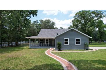 Charming home with a covered porch and a brick walkway leading to the entrance on a large lawn at 3287 Rackley Rd, Brooksville, FL 34604