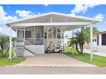 Charming home featuring a covered carport, grill, manicured lawn, and delightful landscaping with palm trees at 3333 26Th E Ave # 1104, Bradenton, FL 34208