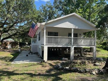 Inviting raised bungalow with a porch, American flag, and nestled amid trees on a well-kept lot at 35236 Reynolds St, Dade City, FL 33523