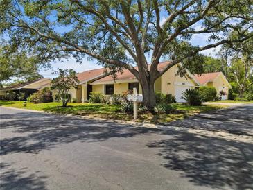 Charming single-story home with a well-manicured lawn and a large, mature tree providing shade at 4203 Carriage Dr # 27, Sarasota, FL 34241