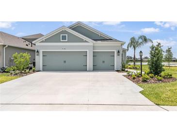 Beautiful, light-blue home showcasing a well-manicured lawn and a three-car garage at 4406 Rustling Pines Ter, Parrish, FL 34219