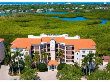Luxury condo building boasts a red tile roof and lush green surroundings with waterfront views at 5420 Eagles Point Cir # 106, Sarasota, FL 34231
