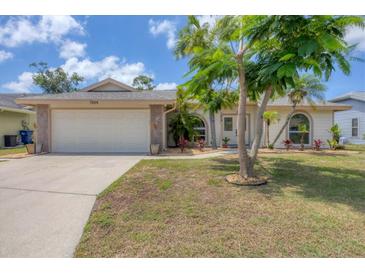 Charming single-story home featuring a two-car garage and tropical landscaping, with a well-maintained lawn at 7834 38Th E Ct, Sarasota, FL 34243