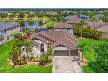 Stunning lakefront home with lush landscaping, a paver driveway, and a spacious three-car garage at 12644 20Th E St, Parrish, FL 34219