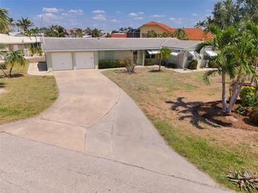 Charming single-story home with a two-car garage, well-manicured lawn, and beautiful palm trees at 135 Gulfview Rd, Punta Gorda, FL 33950