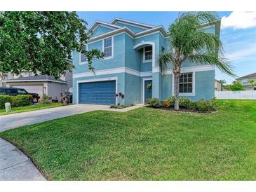 Charming two-story home with a blue exterior, well-manicured lawn, and mature palm tree at 1721 Palm Warbler Ln, Ruskin, FL 33570